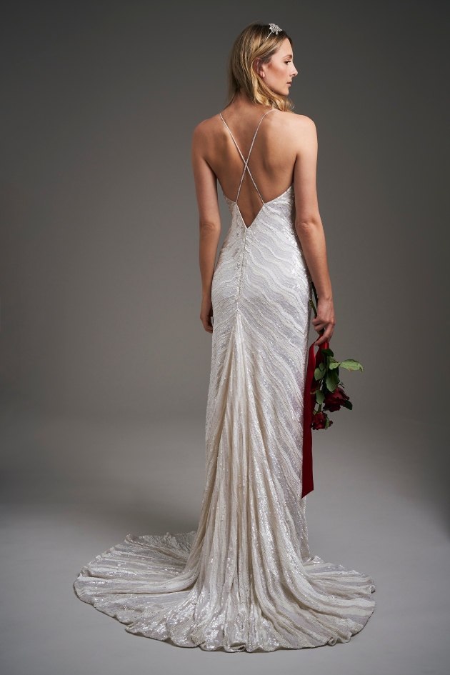back shot of model wearing a wedding dress holding flowers 