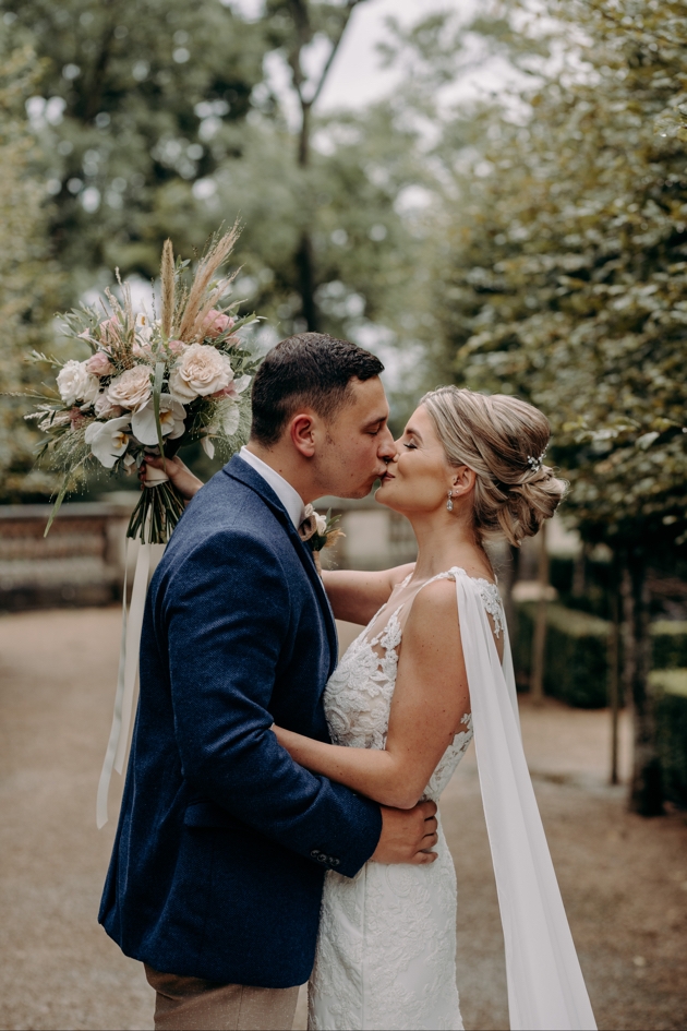 Bride kisses groom with bouquet from The Floral Cheyne