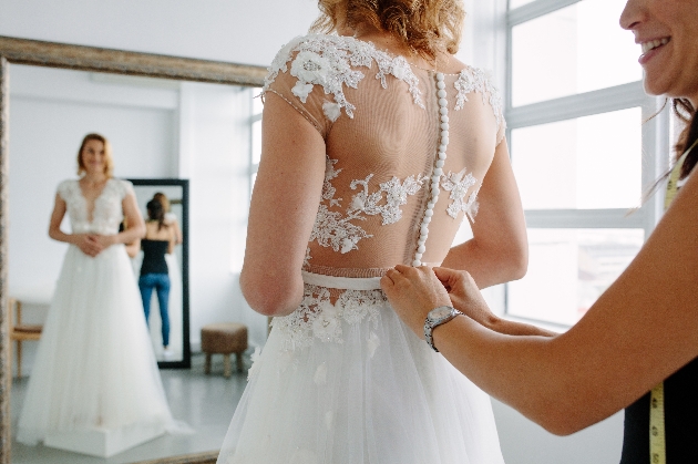 Bride models dress in front of mirror at dress fitting
