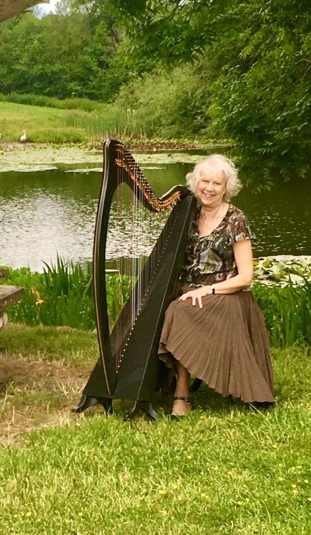 Helen Barley with her Harp in front of a lake