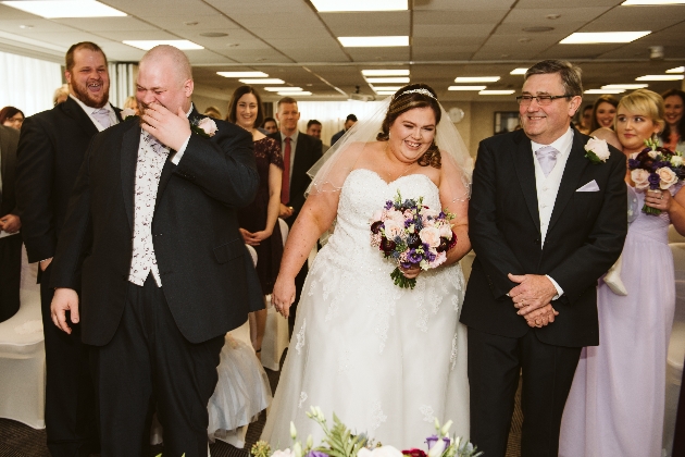 Groom laughs at altar with bride and bride's father