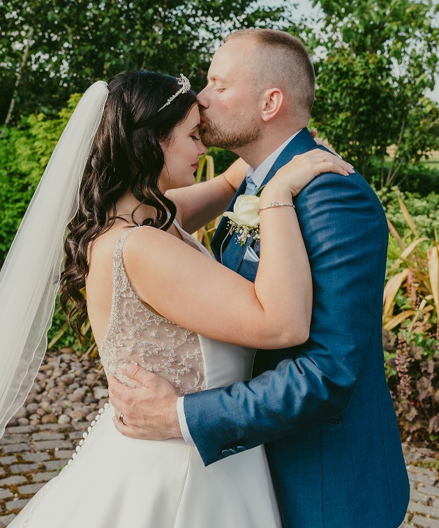 Groom kissing bride's forehead