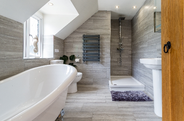 modern bathroom with grey tiles floor to ceiling towel rail and white bathroom suite