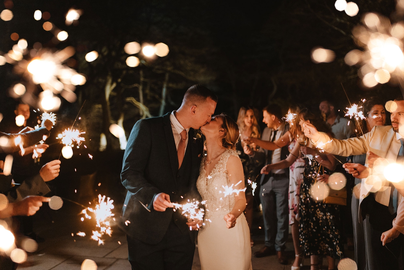 Bride and groom kiss surrounded by sparklers