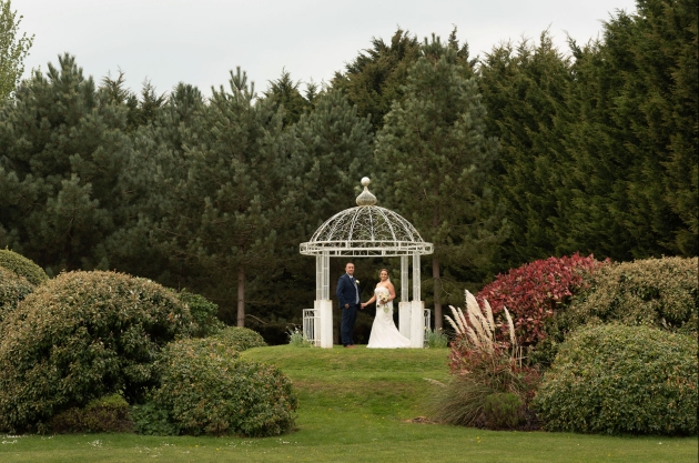 Bride and groom holding hands under a pergola