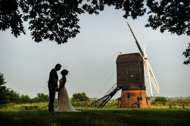 Bride and groom standing in front of a windmill