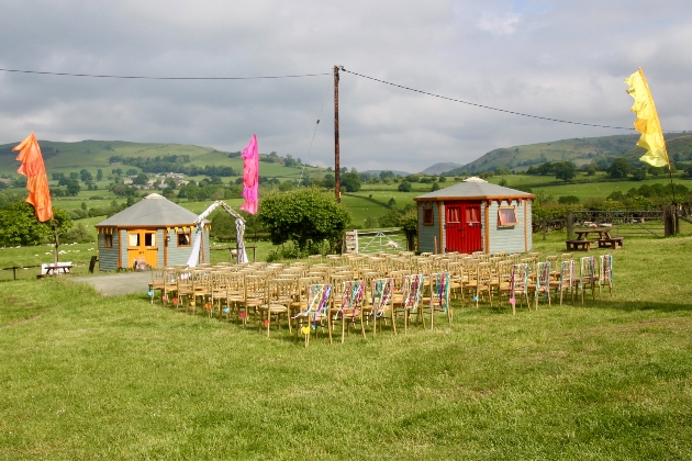 Wooden chairs lined up in several rows on grass overlooking the surrounding countryside