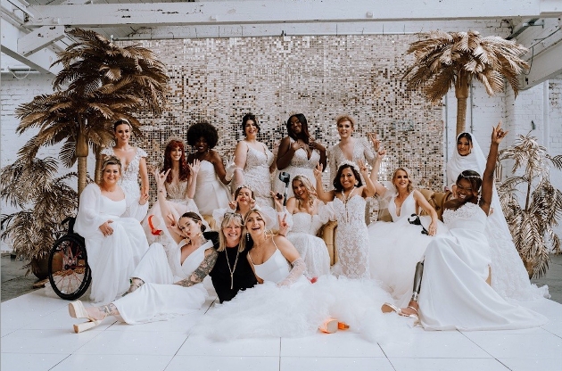 A group of women wearing wedding dresses smiling at the camera
