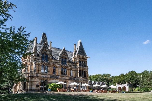 A grand Neo-Gothic mansion with outdoor furniture outside of it