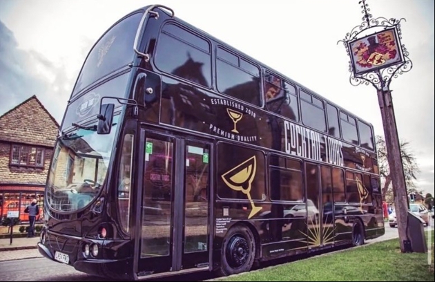 A black double decker bus with Cocktail Tours written on the side
