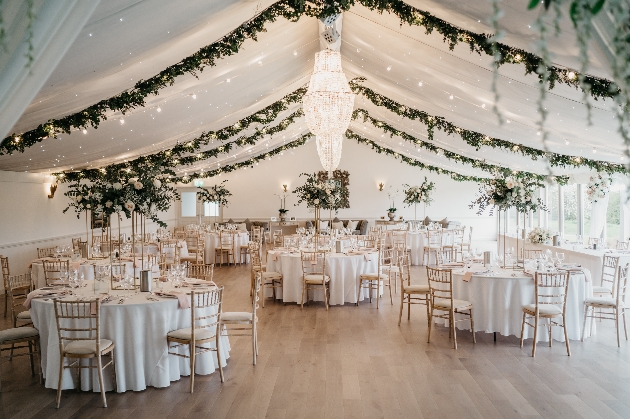 The inside of a large marquee with round tables and flowers