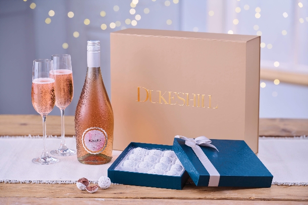 A pink box next to a pink drink, two glasses and a box of truffles