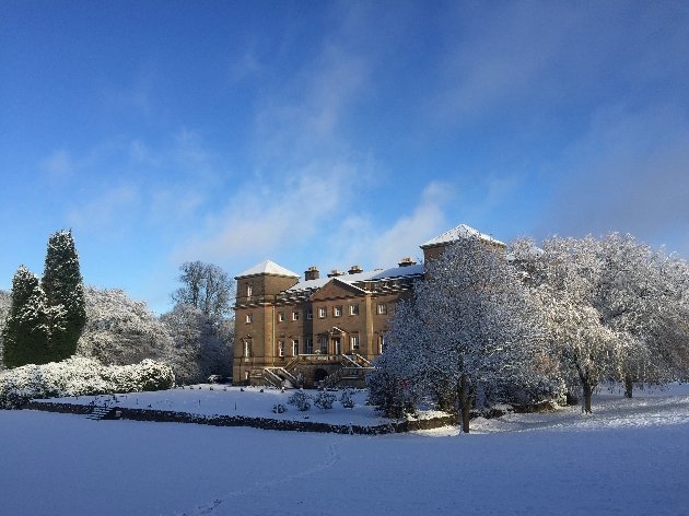 A large manor house surrounded by trees and snow