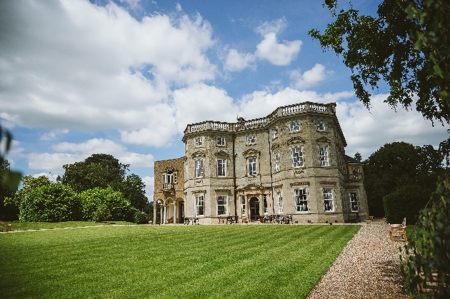 The exterior of a large manor house surrounded by grass